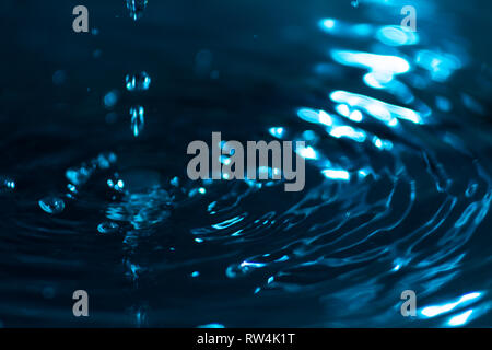 Splash von Wassertropfen auf einer Wasseroberfläche farbige mit himmlischen Tinte. Konzept von Reinheit, Sauberkeit und Erhaltung von nicht erneuerbaren Ressourcen. Abstr Stockfoto