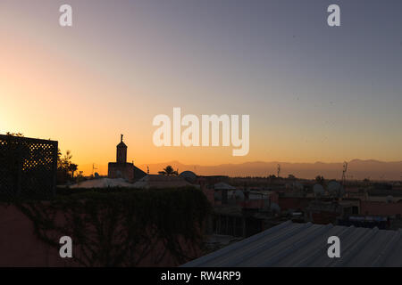 Sunrise/Dämmerung über den Dächern von Marrakesch mit malerischen Moschee und roten glooming Himmel vor dem Atlasgebirge (Marrakesch, Marokko, Afrika) Stockfoto