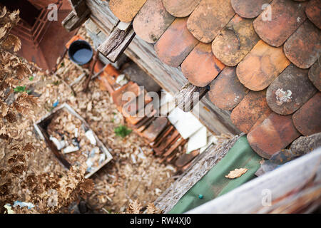 Blick aus einem alten Dach auf Fliesen und Garten voll mit alten Sachen in Unschärfe. Dorf lifestyle Details. Stockfoto