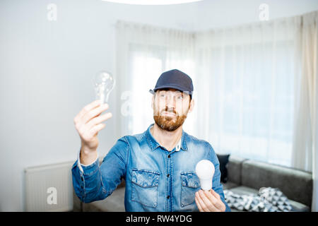 Heimwerker die Wahl zwischen Energie sparen und billig Glühlampe während wechselnde Licht im Appartement Stockfoto