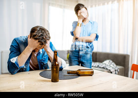 Betrunkene Menschen Alkoholkrank deprimiert zu Hause sitzen mit jungen Frau in Verzweiflung auf dem Hintergrund Stockfoto