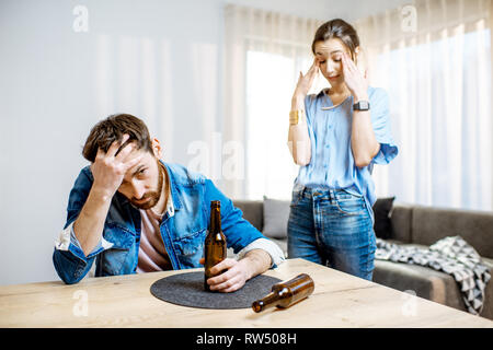 Betrunkene Menschen Alkoholkrank deprimiert zu Hause sitzen mit jungen Frau in Verzweiflung auf dem Hintergrund Stockfoto