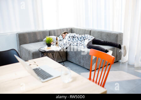 Betrunkener Mann auf der Couch liegen mit Decke, leiden unter dem Alkoholismus zu Hause Stockfoto