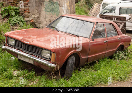 Alten ausrangierten rostigen Auto auf grünem Gras Hintergrund. Gebrochen und vergessen. Ein altes verworfen verrostet Schrott Auto, die abgebrochen wurde. Stockfoto