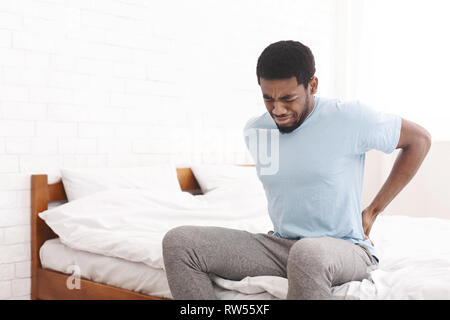 Menschen mit Rückenbeschwerden zu Hause im Schlafzimmer. Stockfoto