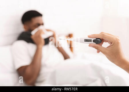 Schwarzer Mann mit Fieber im Bett lag krank Stockfoto