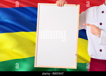 Mauritius Küchenchef Holding leeres Whiteboard Menü auf Mauritius Flagge Hintergrund. Cook tragen einheitliche zeigt Platz für Text. Stockfoto