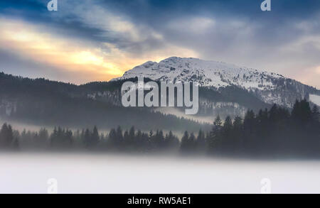 Nebeliger morgen im Berg mit Schnee bedeckt Alp Mountain Top Stockfoto