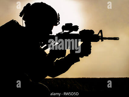 Silhouette der junge Soldat in der militärischen Helm gegen die Sonne. Stockfoto