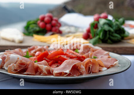 Platte mit Schinken auf Tisch, Radieschen im Hintergrund Stockfoto