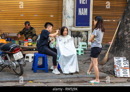 Frau, die einen Haarschnitt von einer Straße, Friseur, Altstadt, Hanoi, Vietnam, Asien Stockfoto