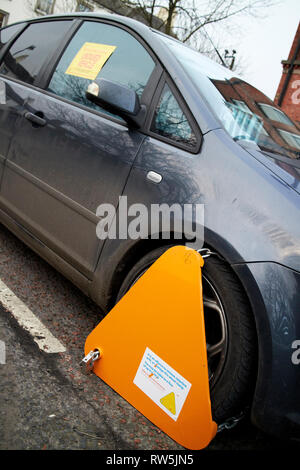 Gelbe wheelclamp auf unversteuerten Fahrzeug Auto auf einer Straße in Großbritannien geklemmt Stockfoto