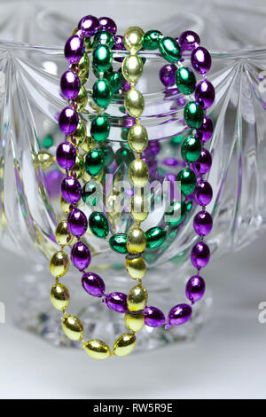 Makro Zusammenfassung von traditionellen drei Farbe Mardi Gras Perlen drapiert über wunderschöne Kristallglas Stockfoto