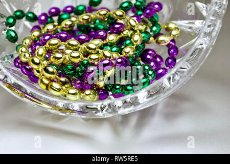 Makro Zusammenfassung von traditionellen drei Farbe Mardi Gras Perlen Einstellung in einem schönen Kristallglas Stockfoto