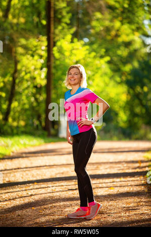 Sportliche Frau, die im Park unter Bäumen auf Sommermorgen. Stockfoto