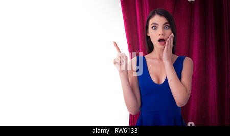 Hübsche Frau vor der roten Vorhängen zeigt etwas über die Theateraufführung. Auf weissem Hintergrund Stockfoto