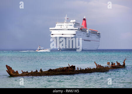 Das Motorboot vorbei zwischen driften Kreuzfahrtschiff und Überreste einer versunkenen Schiff am Seven Mile Beach, Grand Cayman Island (Cayman Inseln). Stockfoto