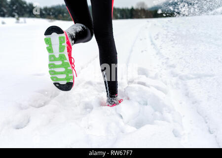 Teenager, die auf tiefen Schnee im Winter Berge. Fokus auf der Sohle des Schuhs - Läufer Joggen im Schnee Stockfoto