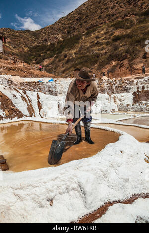 Maras, Cusco, Peru, August 2018: Ein nicht identifizierter Arbeiter extrahiert das Salz von der Verdampfung pools in Maras, eine Mine, die für Cent ausgenutzt wurde. Stockfoto