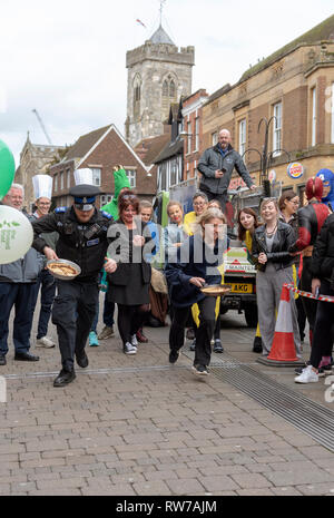 Salisbury, Wiltshire, UK. 5 Mär, 2019. Wettbewerber in den jährlichen Pfannkuchen Rennen an der High Street, Salisbury konkurrieren. Die Veranstaltung wird von St. Thomas Kirche und die trussell Trust organisiert. Stockfoto