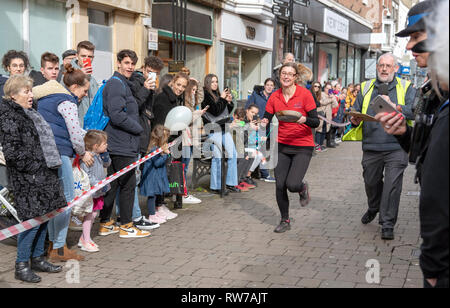 Salisbury, Wiltshire, UK. 5 Mär, 2019. Wettbewerber in den jährlichen Pfannkuchen Rennen an der High Street, Salisbury konkurrieren. Die Veranstaltung wird von St. Thomas Kirche und die trussell Trust organisiert. Stockfoto