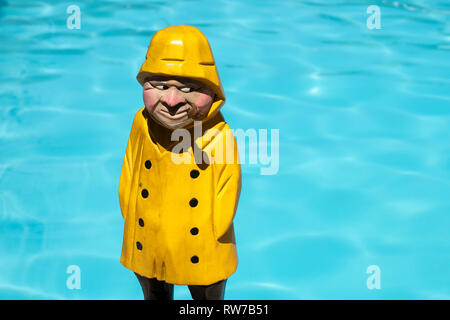 Fischer Holzfigur mit gelben Regenmantel und Rauch am Pool Hintergrund. Platz kopieren Stockfoto