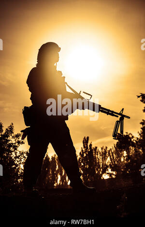 Silhouette der junge Soldat in der militärischen Helm gegen die Sonne. Stockfoto