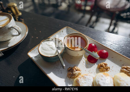 Quark Pfannkuchen mit saurer Sahne, Honig auf dem Tablett. Stockfoto