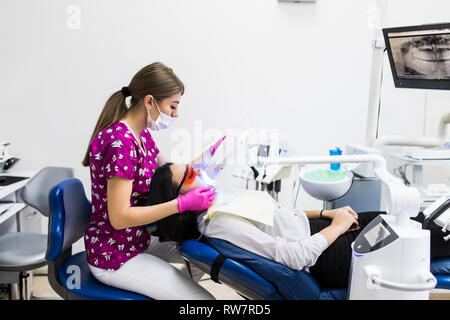 Close-up Portrait einer Patientin beim Zahnarzt in der Klinik. Zahnweiß-Verfahren mit UV-Licht UV Lampe. Stockfoto