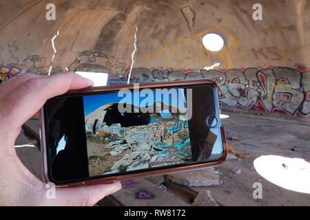 Ein Blick auf die Außenseite der Ruinen von Casa Grande wie auf einem iPhone gesehen, während Sie in den Graffiti gefüllte Höhlen. Stockfoto