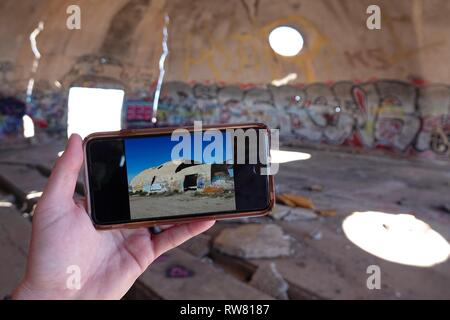 Ein Blick auf die Außenseite der Ruinen von Casa Grande wie auf einem iPhone gesehen, während Sie in den Graffiti gefüllte Höhlen. Stockfoto