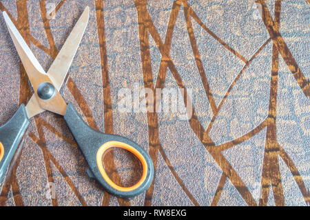 Blick von oben auf eine Schere auf einer strukturierten braun Tabelle gehalten. Platz für Text Stockfoto