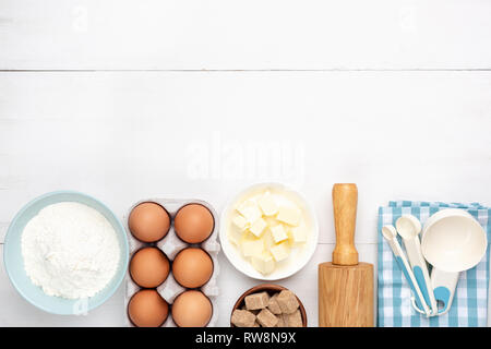 Eier, Mehl, Butter und Zucker. Backzutaten auf weißem Holzbohlen Hintergrund. Ansicht von oben mit Platz für Text Stockfoto