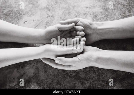 Junge Familie Hand in Hand mit Hilfe, Schutz und Unterstützung Symbol. Gemeinsame Hoffnung Konzept Stockfoto