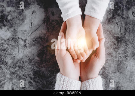 Licht in der jungen Familie Hände mit Hilfe, Schutz und Unterstützung Symbol. Gemeinsame Hoffnung Konzept Stockfoto