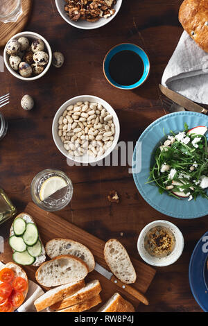 Leckeres und gesundes Frühstück oder Mittagessen. Verschiedene Snacks, Vorspeisen, Rucola Salat, Sandwiches mit Schinken und Gemüse auf dunklen Holz- backgrou Stockfoto