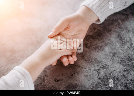 Nahaufnahme der Familie halten sich an den Händen, liebevolle fürsorgliche Mutter, Kind. Helfende Hand und hoffen, Konzept und Internationalen Tag des Friedens Stockfoto