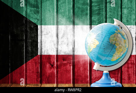 Globus mit einer Weltkarte auf einem hölzernen Hintergrund mit dem Bild der Flagge von Kuwait. Das Konzept der Reisen und Freizeit im Ausland. Stockfoto