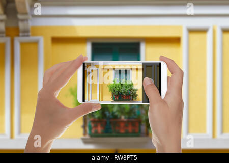 Ein Mann macht ein Foto von dem Fenster eines der Häuser im Zentrum von Mailand ist mit Blende und mit Blumen auf einem Mobiltelefon eingerichtet Stockfoto