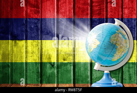 Globus mit einer Weltkarte auf einem hölzernen Hintergrund mit dem Bild der Flagge von Mauritius. Das Konzept der Reisen und Freizeit im Ausland. Stockfoto