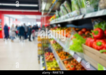 Abstrakte verschwommen Supermarkt Gang. Kunden unkenntlich als Hintergrund. Obst und Gemüse in den Regalen im Supermarkt Stockfoto