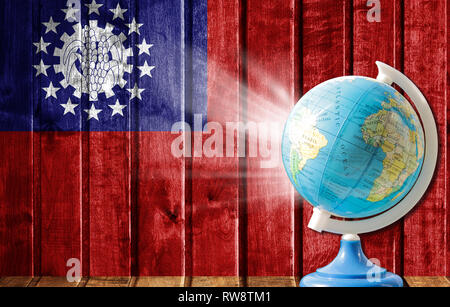 Globus mit einer Weltkarte auf einem hölzernen Hintergrund mit dem Bild der Flagge von Myanmar. Das Konzept der Reisen und Freizeit im Ausland. Stockfoto