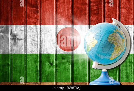Globus mit einer Weltkarte auf einem hölzernen Hintergrund mit dem Bild der Flagge von Niger. Das Konzept der Reisen und Freizeit im Ausland. Stockfoto