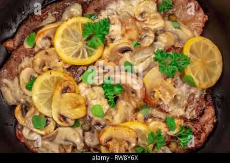 Eine Nahaufnahme von scallopine di Vitello, Kalbfleisch scallopini, mit Pilzsauce, Zitronen, und Petersilie, Schuß von der Oberseite Stockfoto