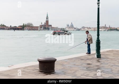 Ein Ältester Mann angeln in Venedig. Ein Fischer in Venedig Canal. Italien Stockfoto