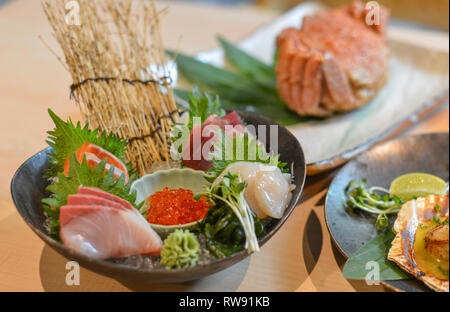 Gemischte sashimi Fisch in Scheiben geschnitten auf Eis im schwarzen Schüssel am traditionellen japanischen Restaurant. Stockfoto