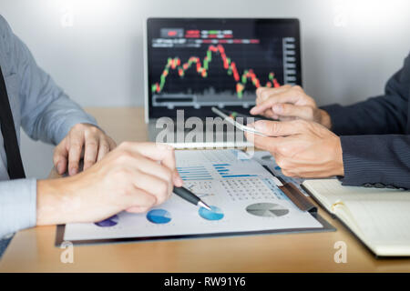 Die Unternehmer sprechen über Börse investieren Trading online Analyse ueber finanzielle Graph für Investitionszwecke Diskussion im Traders Büro Stockfoto