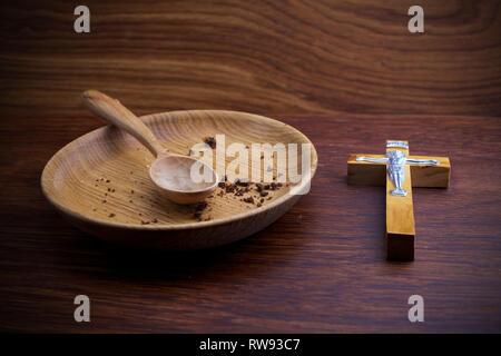 Fasten, Fastenzeit. Platte und Kreuz auf Holz- Hintergrund. Stockfoto