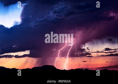 Malerische Wüstenlandschaft mit einem Blitzschlag, der bei Sonnenuntergang in einer Gewitterwolke in der Nähe von Bagdad, Arizona, auffällt Stockfoto