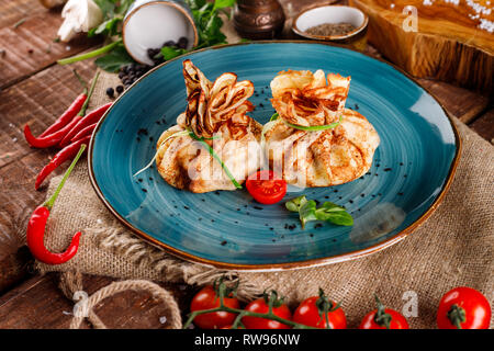 Pfannkuchen mit Lachs, Frischkäse und Kräutern. Beutel mit Dill auf einem blauen Schild an einem Holztisch Hintergrund gebunden Stockfoto